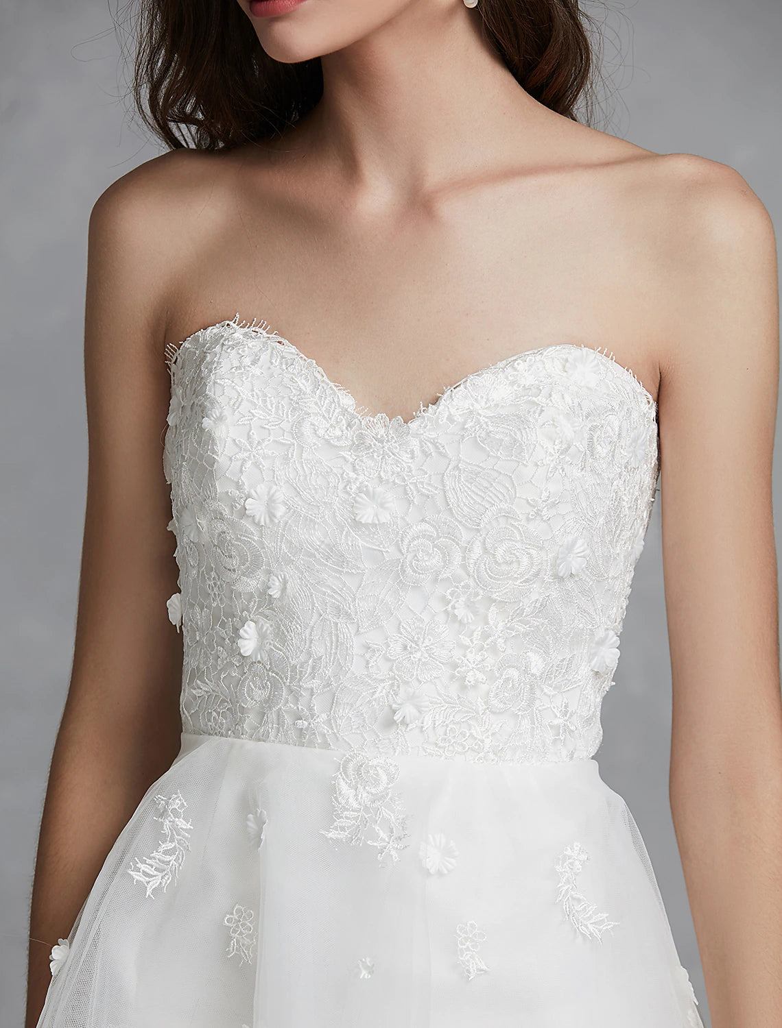 Side view of A-Line sweetheart strapless white reception bridal gown with asymmetrical hem.