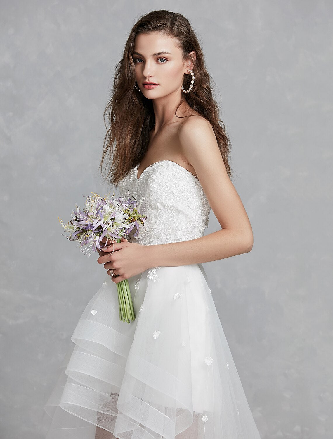 Detail of asymmetrical hem on white A-Line reception bridal gown.
