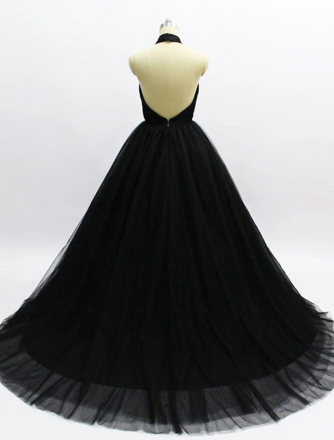 Side view of a model in an elegant halter ball gown prom dress, highlighting the court train and pleats.