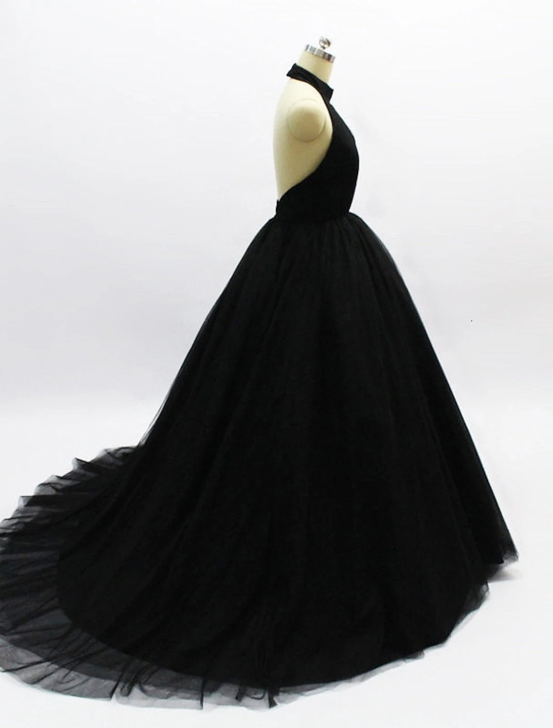 Back view of a model in an elegant halter ball gown prom dress, showcasing the open back and tulle details.