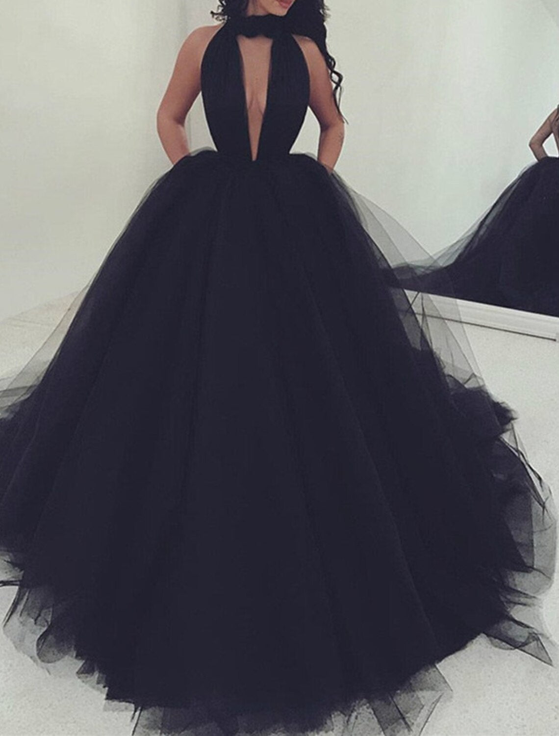 Full-length view of an elegant halter ball gown prom dress with an open back, tulle, and pleats.