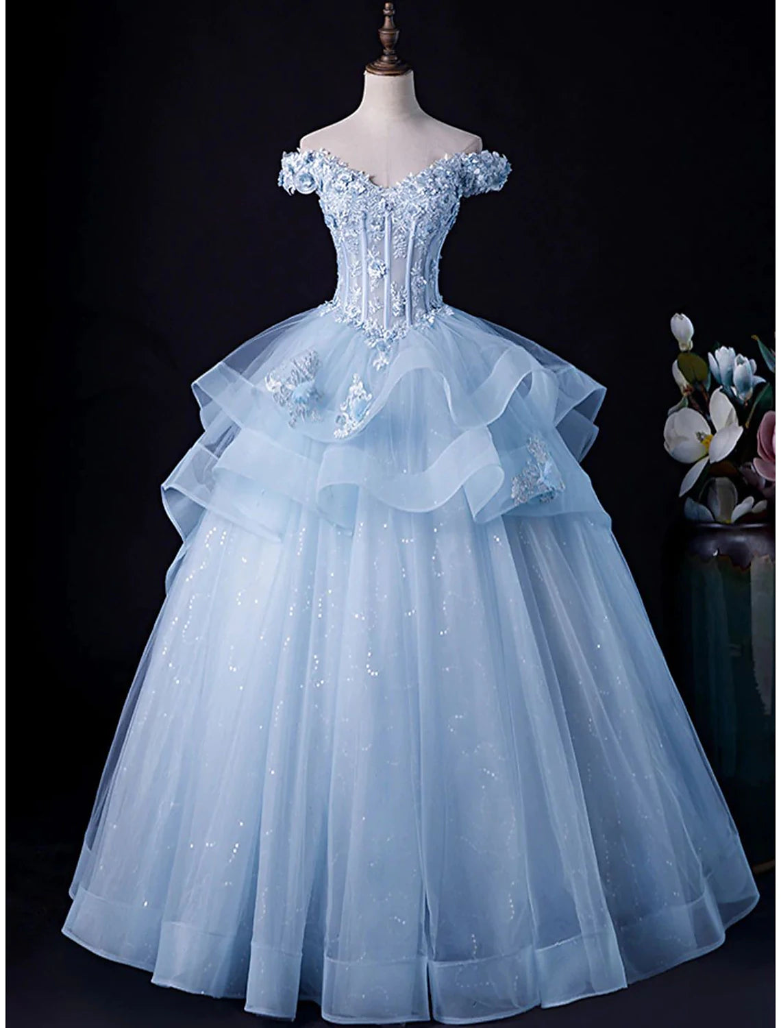 Model wearing an elegant off-shoulder ball gown with a floor-length tulle skirt.