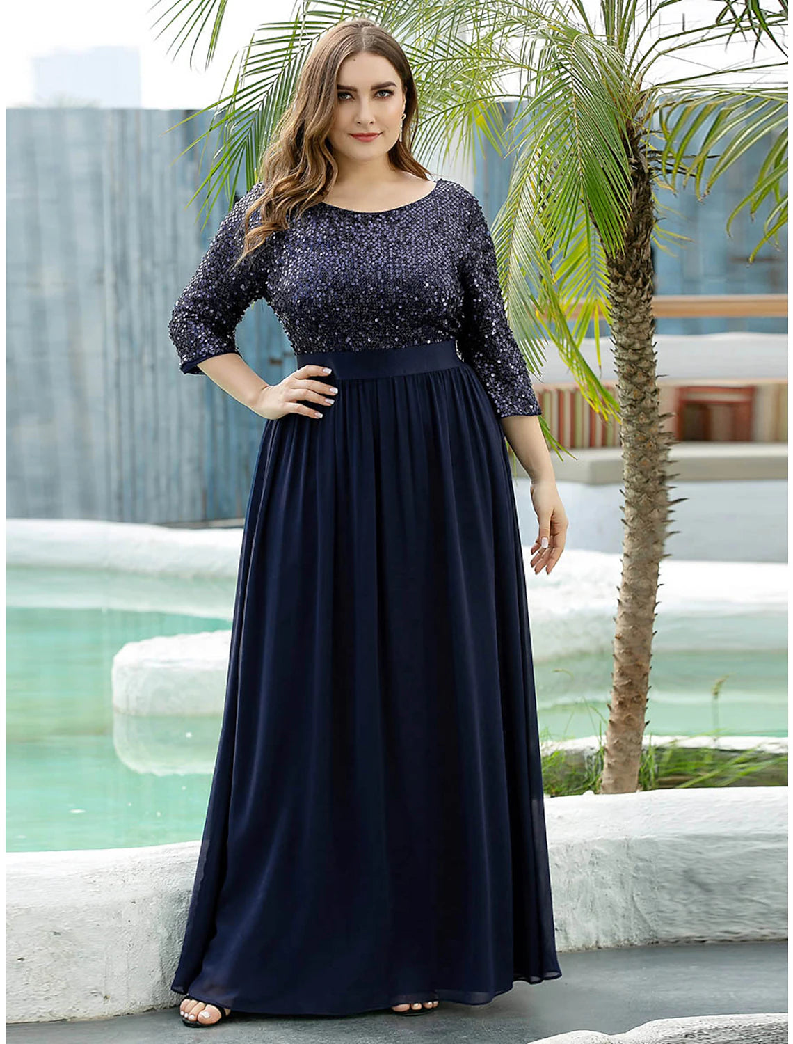 Model walking in an elegant plus size A-line jewel neck sequined tulle gown.