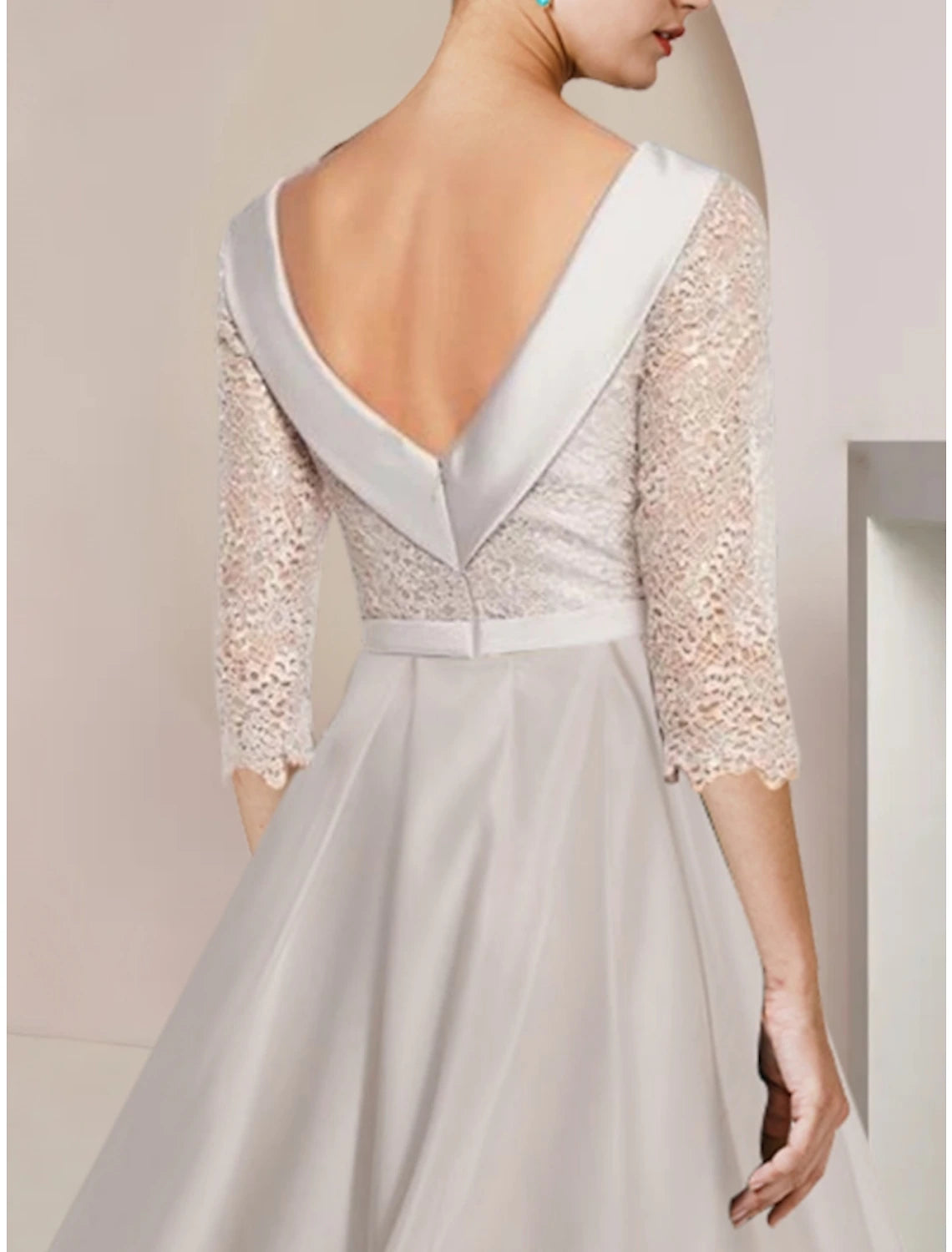 Back view of an elegant sheath dress with a scoop neck and tea-length silhouette.