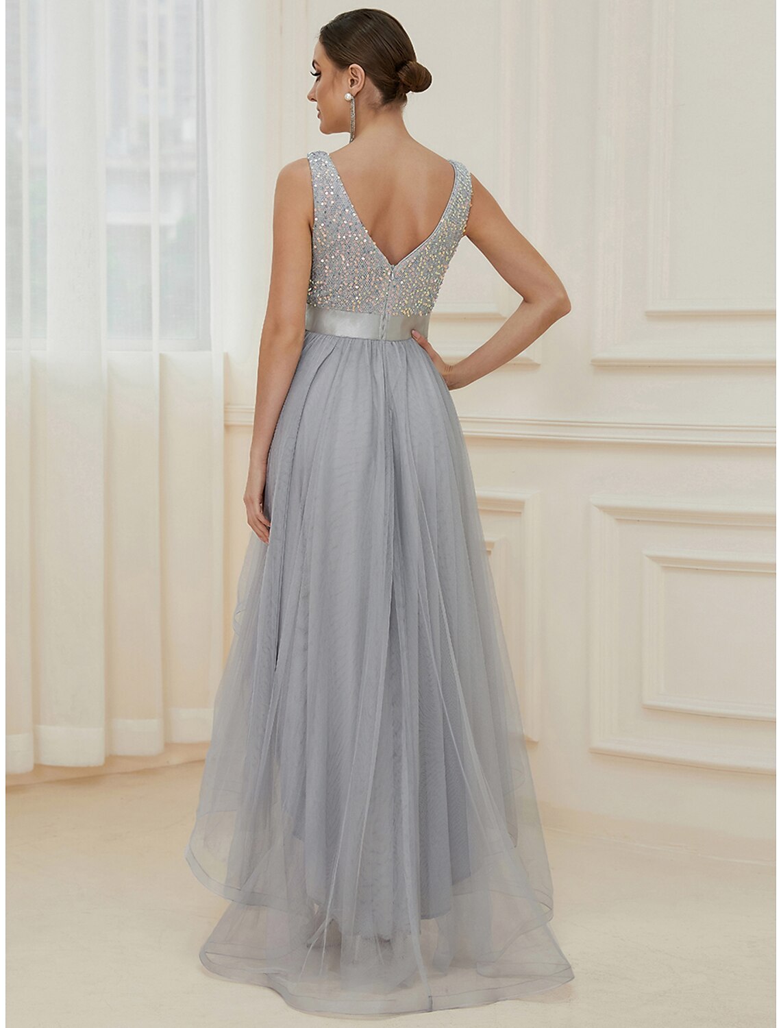 Full length view of a sparkling A-line V-neck sequin tiered champagne maxi bridesmaid gown.